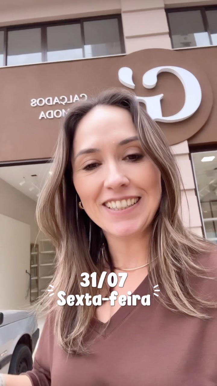 Fundadora sorrindo em frente à loja nova com a data 31/07